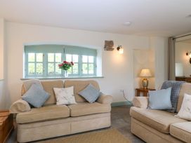A living room with two sofas and a flower vase on the window sill at No 2 The Stables Capel Coch near Llannerch-Y-Medd