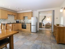 A kitchen with wooden cabinets and a table at No 2 The Stables Capel Coch near Llannerch-Y-Medd
