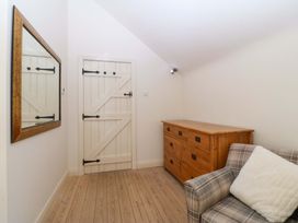 A room with a mirror, chest of drawers, and a sofa at No 2 The Stables in Capel Coch near Llannerch-Y-Medd