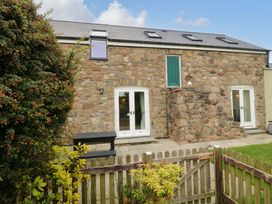 A stone building with windows and doors in an outdoor area at No 2 The Stables Capel Coch near Llannerch-Y-Medd