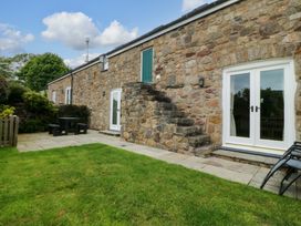 An outdoor area with stone walls and seating arrangements at No 2 The Stables Capel Coch near Llannerch-Y-Medd