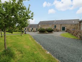 A gravel driveway with buildings and trees at No 2 The Stables Capel Coch near Llannerch-Y-Medd