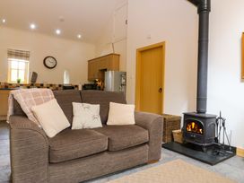 A living room with a sofa and stove at No 3 The Dairy Capel Coch near Llannerch-Y-Medd