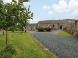 An outdoor area with stone buildings and trees at No 3 The Dairy Capel Coch near Llannerch-Y-Medd