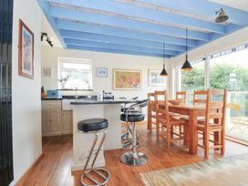 A kitchen with bar stools and a dining table at Beachside in Polzeath