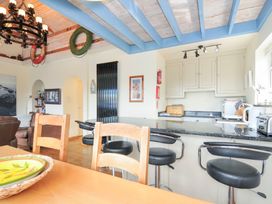 A kitchen with a dining table and bar stools at Beachside in Polzeath