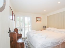 A bedroom with a bed and window shutters at Beachside in Polzeath