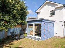 A garden with a blue house and chairs at Beachside in Polzeath