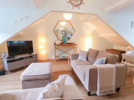 A living room with a television and a sofa at Smugglers Loft in Looe