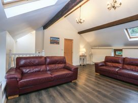 A living room with two leather sofas and a lamp at Llofft Yr Yd Porthmadog
