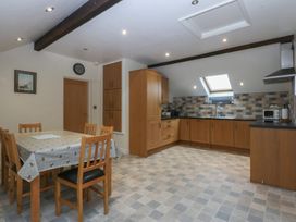 A kitchen with a dining area and wooden cabinets at Llofft Yr Yd Porthmadog