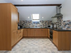 A kitchen with wooden cabinets and a stove at Llofft Yr Yd Porthmadog