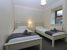 A bedroom with two beds and a lamp at Llofft Yr Yd in Porthmadog