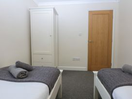 A bedroom with two beds and a wardrobe at Llofft Yr Yd Porthmadog