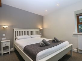 A bedroom with a bed and bedside table at Llofft Yr Yd in Porthmadog