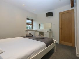 A bedroom with a bed and a mirror at Llofft Yr Yd Porthmadog