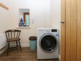 A laundry room with a washing machine and a chair at Llofft Yr Yd Porthmadog