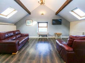 A living room with sofas and a television at Llofft Yr Yd in Porthmadog