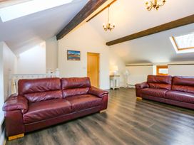 A living room with two sofas and a lamp at Llofft Yr Yd Porthmadog