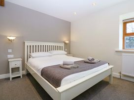 A bedroom with a bed and a nightstand at Llofft Yr Yd in Porthmadog