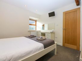 A bedroom with a bed, dresser, and mirror at Llofft Yr Yd in Porthmadog