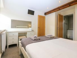 A bedroom with a bed and dresser at Llofft Yr Yd in Porthmadog