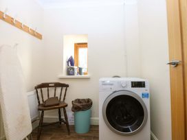 A utility room with a washing machine and an ironing board at Llofft Yr Yd in Porthmadog