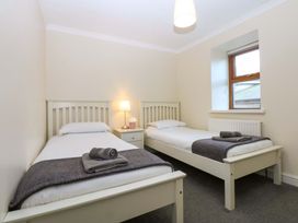 A bedroom with two single beds and a lamp at Llofft Yr Yd in Porthmadog