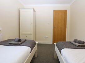 A bedroom with two beds and a wardrobe at Llofft Yr Yd in Porthmadog