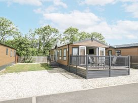 A mobile home with a porch and decking in a gravel area at Serendipity