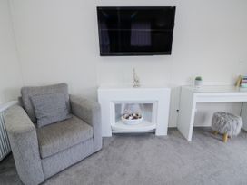 A living room with a television and an armchair at Serendipity