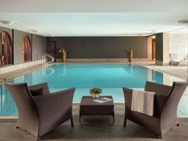 An indoor swimming pool area with chairs and a table at Cosy Corner in the Lakes Greystoke