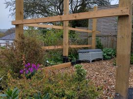 A garden with a wooden structure and a bench at Pound Cottage in Uplyme