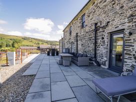 An outdoor seating area with stone wall and patio at Plas Glan Yr Afon in Llangernyw