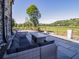An outdoor terrace with seating and a coffee table at Plas Glan Yr Afon in Llangernyw