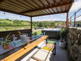 An outdoor area with a wooden table and hot tub at Plas Glan Yr Afon Llangernyw
