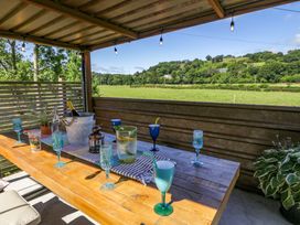 An outdoor dining area with a table set for drinks at Plas Glan Yr Afon Llangernyw