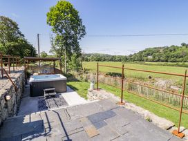 An outdoor space with a hot tub and view of the landscape at Plas Glan Yr Afon in Llangernyw