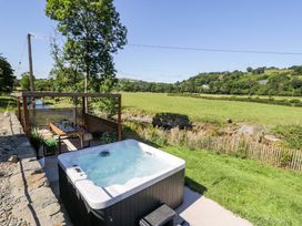 An outdoor area with a hot tub and seating at Plas Glan Yr Afon in Llangernyw