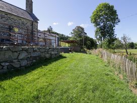 A garden area with grass and stone wall at Plas Glan Yr Afon in Llangernyw