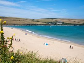 A beach scene with sand, water, and people at Trelowen in St Issey near Padstow