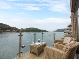 An outdoor seating area overlooking water and hills at Villa 1, Estura Salcombe