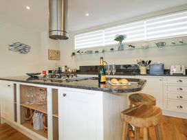 A kitchen with a gas stove and bar stools at Villa 1, Estura Salcombe