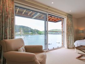 A bedroom with an armchair and a view of the water at Villa 1, Estura, Salcombe