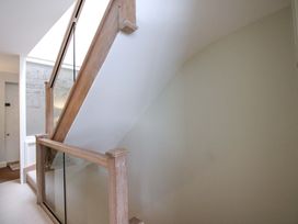 A staircase with a wooden handrail and wall paneling at Villa 1, Estura Salcombe