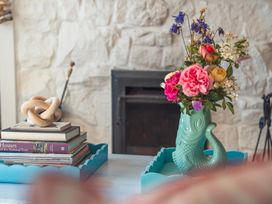 A living room with a vase of flowers and a stack of books at Gerallt in Morfa Nefyn