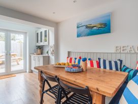 A dining room with a wooden table and striped cushions at Gerallt in Morfa Nefyn