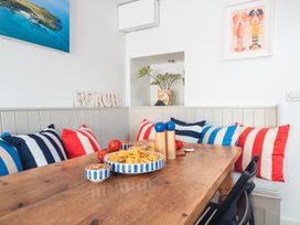 A dining room with a table and decorative cushions at Gerallt in Morfa Nefyn
