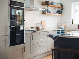 A kitchen with an oven, cups, and a milk bottle at Gerallt in Morfa Nefyn