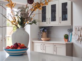 A kitchen with a fruit bowl and flowers on the countertop at Gerallt in Morfa Nefyn